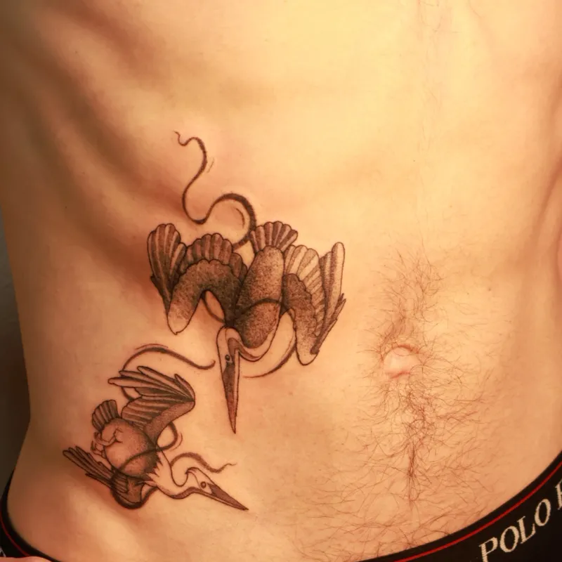 Fine-line twin cranes in flight tattoo on torso